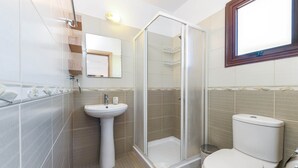A bathroom with a glass-enclosed shower, a pedestal sink, and a toilet. - Nissi Apartment 101 (Ayia Napa)
