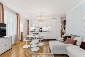 Un salon moderne avec un canapé, une table basse et un coin repas agrémenté d’un lustre.