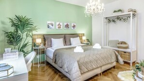Een slaapkamer met een bed, nachtkastjes, een spiegel en een grote plant.