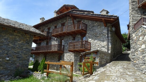 A stone building with wooden balconies and a cobblestone path. - Brenlo (La Salle)