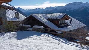 A snow-covered mountain cabin with stone walls and wooden beams, surrounded by a wooden fence and snow-covered ground. - Brenlo (La Salle)