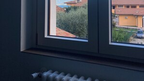 Ein Fenster mit Blick auf einen Berg, ein Gebäude mit rotem Dach und ein geparktes Auto davor.