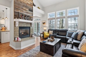 A spacious living room with a fireplace, a sectional sofa, and large windows.
