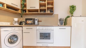 Ett kompakt kök med tvättmaskin, mikrovågsugn, ugn och kylskåp.