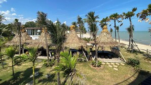 Um resort à beira-mar com guarda-sóis de palha, palmeiras e vista para o oceano.