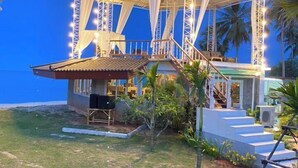 Um edifício à beira-mar com área externa coberta, piscina e escadaria que leva a um terraço.