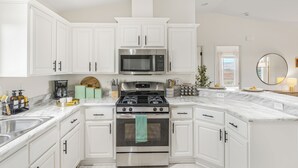 Una cocina moderna con armarios blancos, electrodomésticos de acero inoxidable y encimera de mármol.