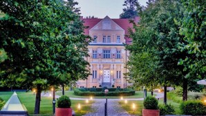 A large, stately building with a symmetrical facade, a central entrance, and a well-maintained garden with a paved pathway leading to the entrance. - Sunday Resort Rugen Superior Double Room (Sagard)