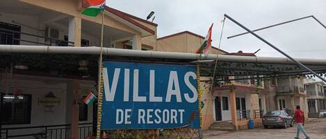 A sign for 'Villas de Resort' with a flag and a fence.