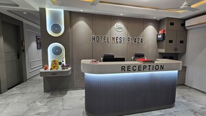 Ein Empfangsschalter mit einem Schild, auf dem 'HOTEL NEST PLAZA RECEPTION' steht, und einem Logo darüber.