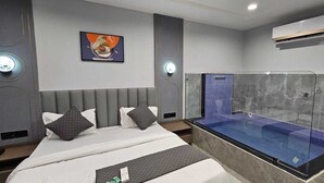 Ein modernes Hotelzimmer mit einem großen Bett, einer integrierten Whirlwanne und einer Klimaanlage.