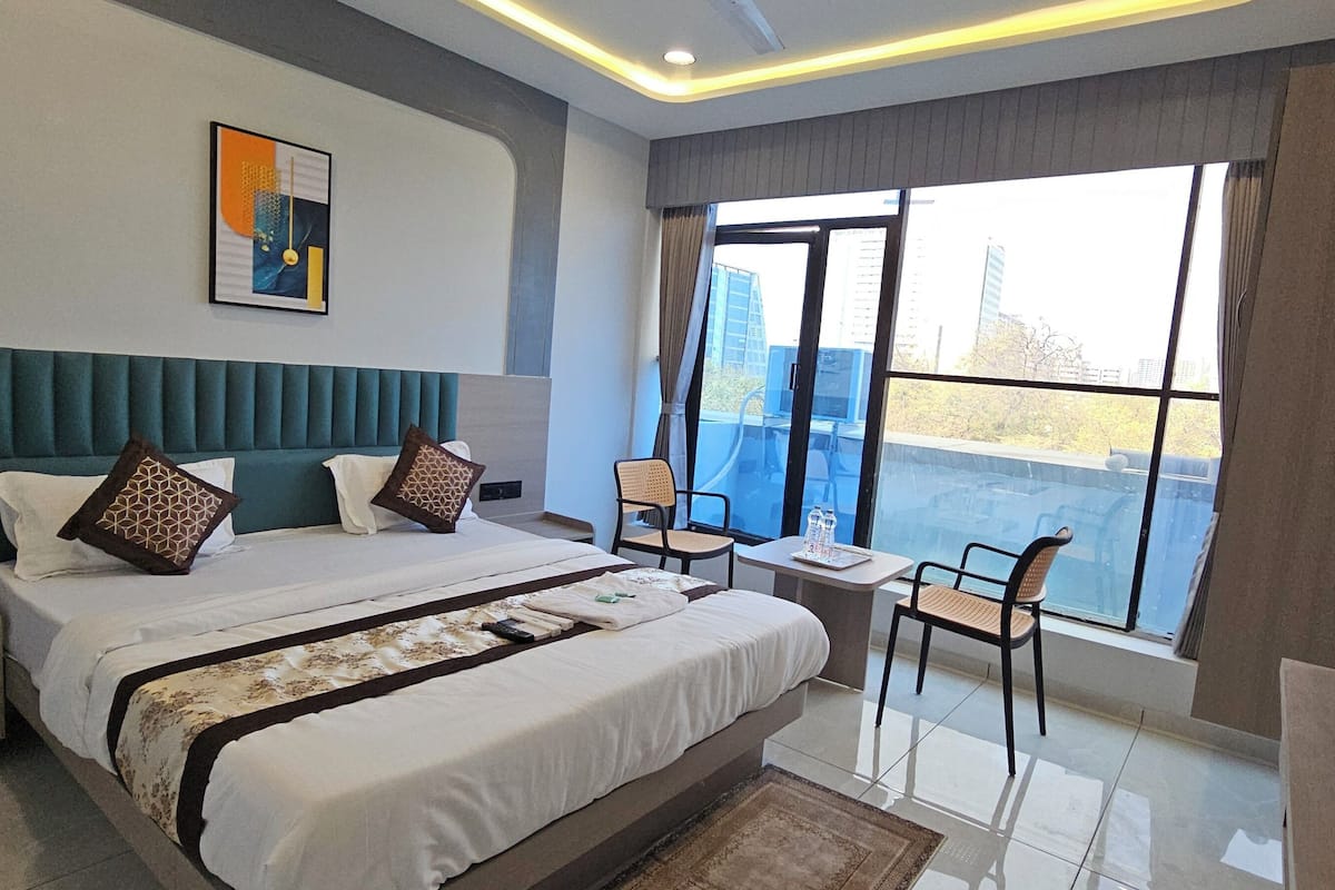 Une chambre d’hôtel moderne avec un grand lit, une petite table, une chaise et un téléviseur.