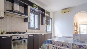 Een moderne keuken met donkere kastjes, een gasfornuis en een groot raam.