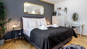 Et moderne soveværelse med en stor seng, sengeborde, en kommode og et spejl.