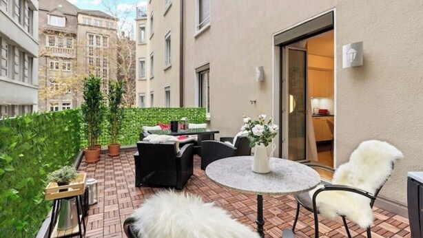 A small patio area with a round table, two chairs, and a sofa. There are potted plants and a small wooden table. - Central | AC | Private Terrace | Free Parking (Zürich)