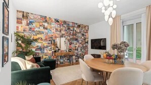 A modern living room with a collage wall, a dining area, and a large window. - Central | AC | Private Terrace | Free Parking (Zürich)
