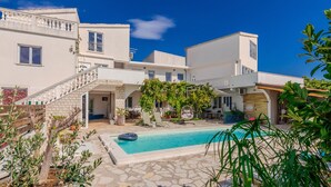 En modern villa med en swimmingpool, utomhusmöbler och en trappa i sten.
