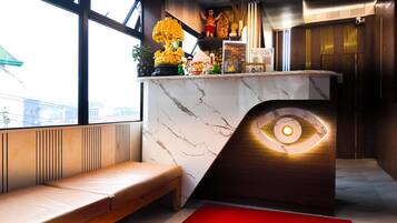 Un intérieur moderne avec un comptoir en marbre, un banc et un élément de design original en forme d’œil.