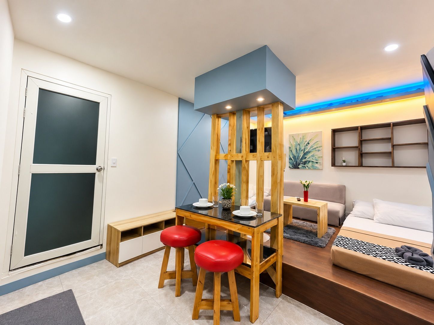 A compact living space with a dining area, a sofa, a bed, and a small table.
