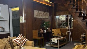 Ein gemütliches Wohnzimmer mit einer Holztreppe, einem Essbereich und einer durch eine offene Tür einsehbaren Küche.