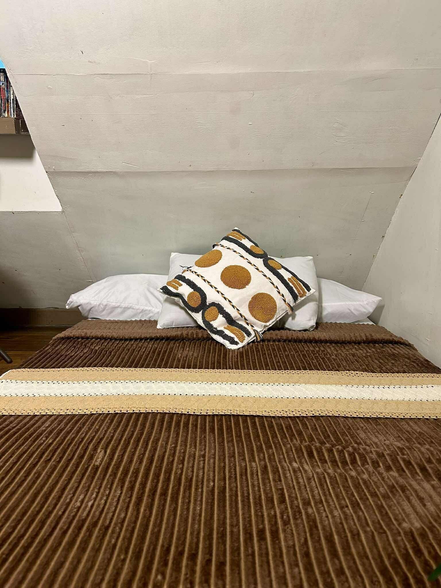 A room with a bed, pillows, and a striped rug.
