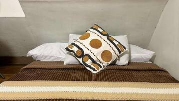 A room with a bed, pillows, and a striped rug.