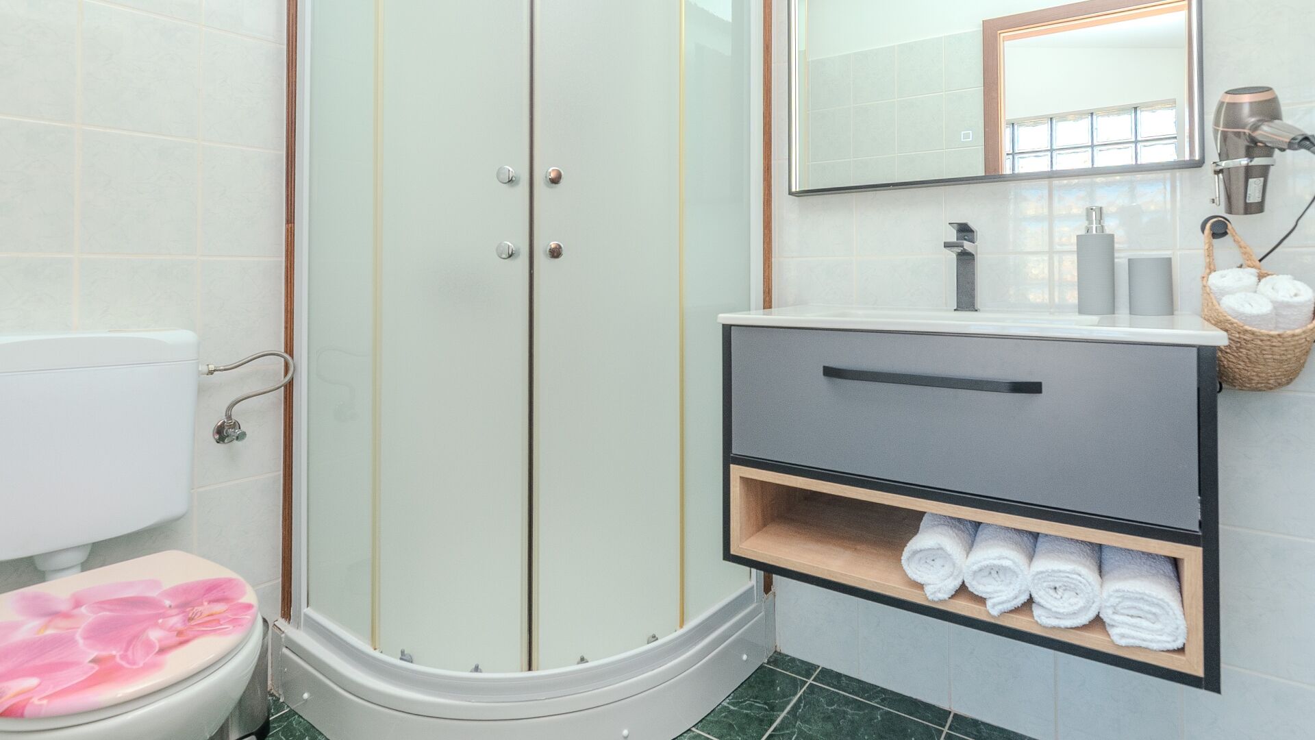 A bathroom with a shower, toilet, and vanity with towels.