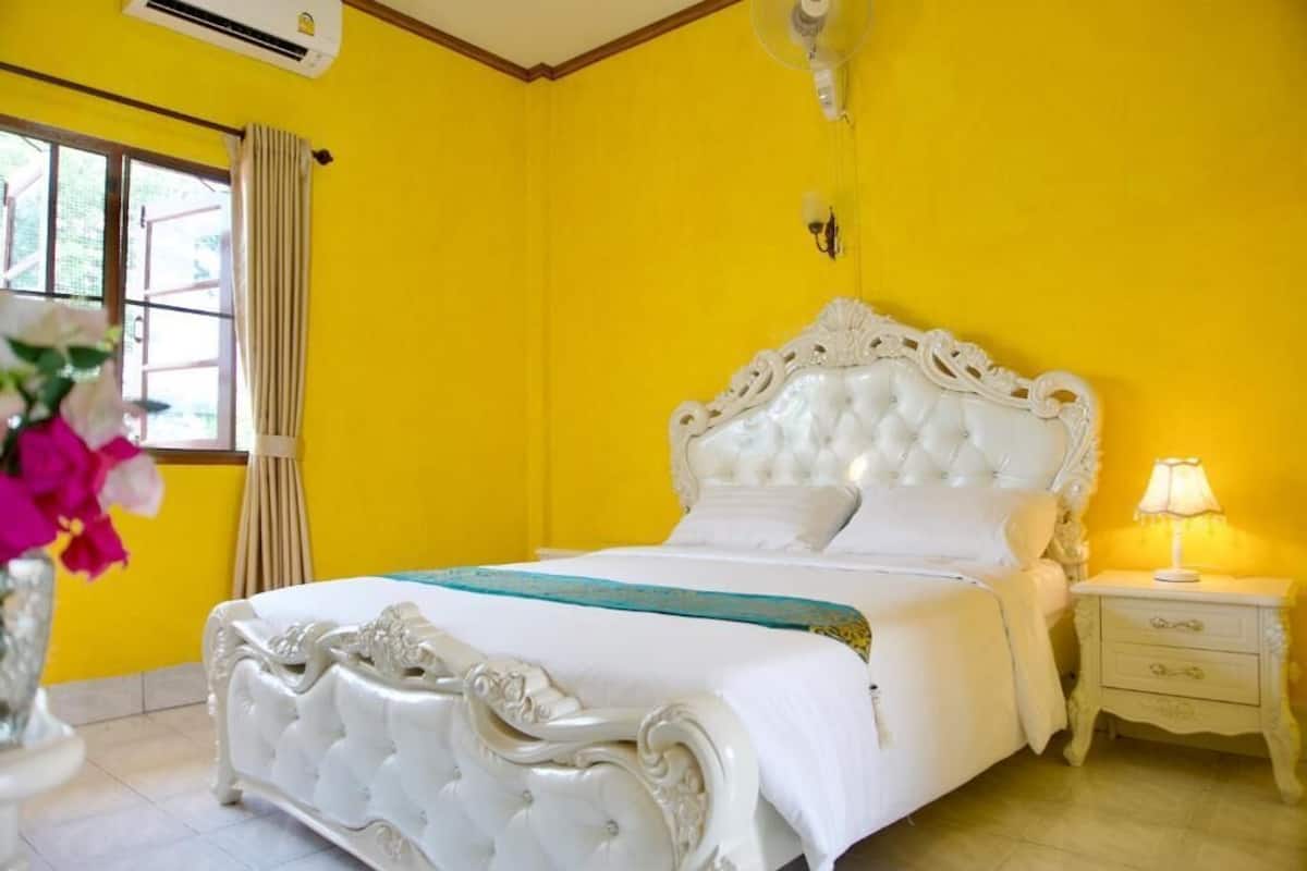 A room with a large bed, a bedside table, and a window with curtains.