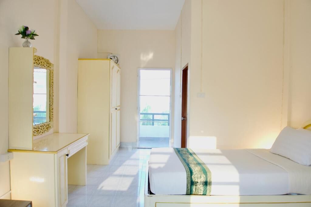 A hotel room with a bed, a desk, a mirror, and a door leading to a balcony.