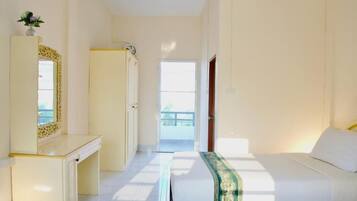 A hotel room with a bed, a desk, a mirror, and a door leading to a balcony.
