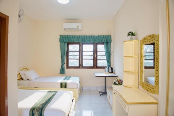 A hotel room with two single beds, a desk, a mirror, and a window with curtains.
