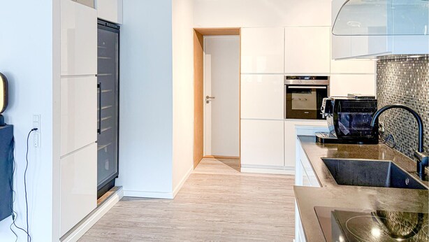 Une cuisine moderne dotée d’appareils électroménagers intégrés, d’un pare-feu en verre et d’un plancher en bois.