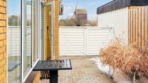 Une terrasse avec une table, une clôture blanche et un moulin à vent en arrière-plan.