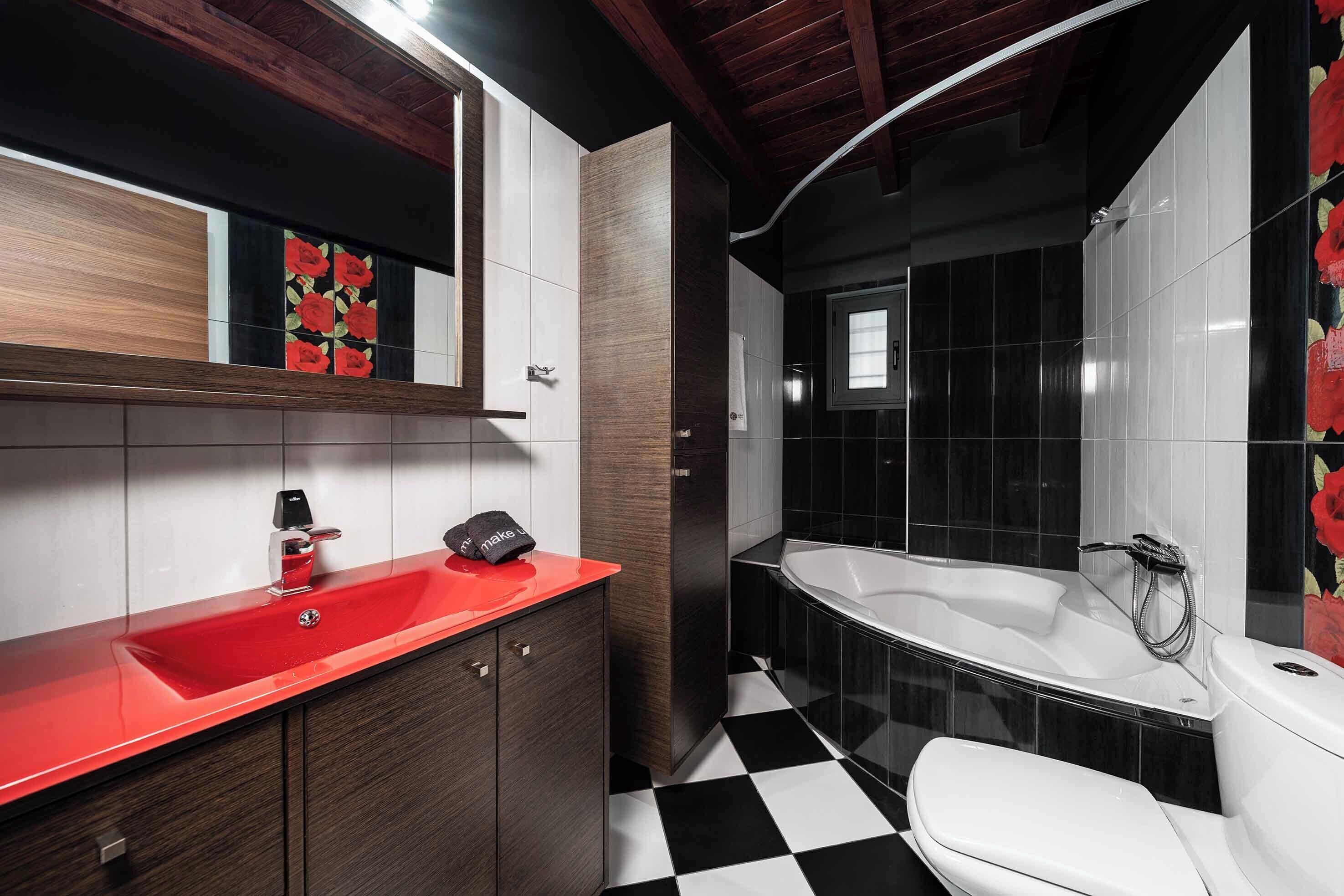 Une salle de bain moderne avec un lavabo rouge, un sol à carreaux noirs et blancs et une grande baignoire.