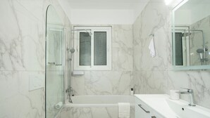 Ein modernes Badezimmer mit einer begehbaren Glasdusche, einer Badewanne und einem Waschtisch.
