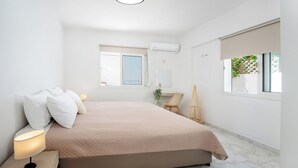 Ein modernes Schlafzimmer mit Bett, Nachttischlampen, Schreibtisch und Fenster mit Blick.