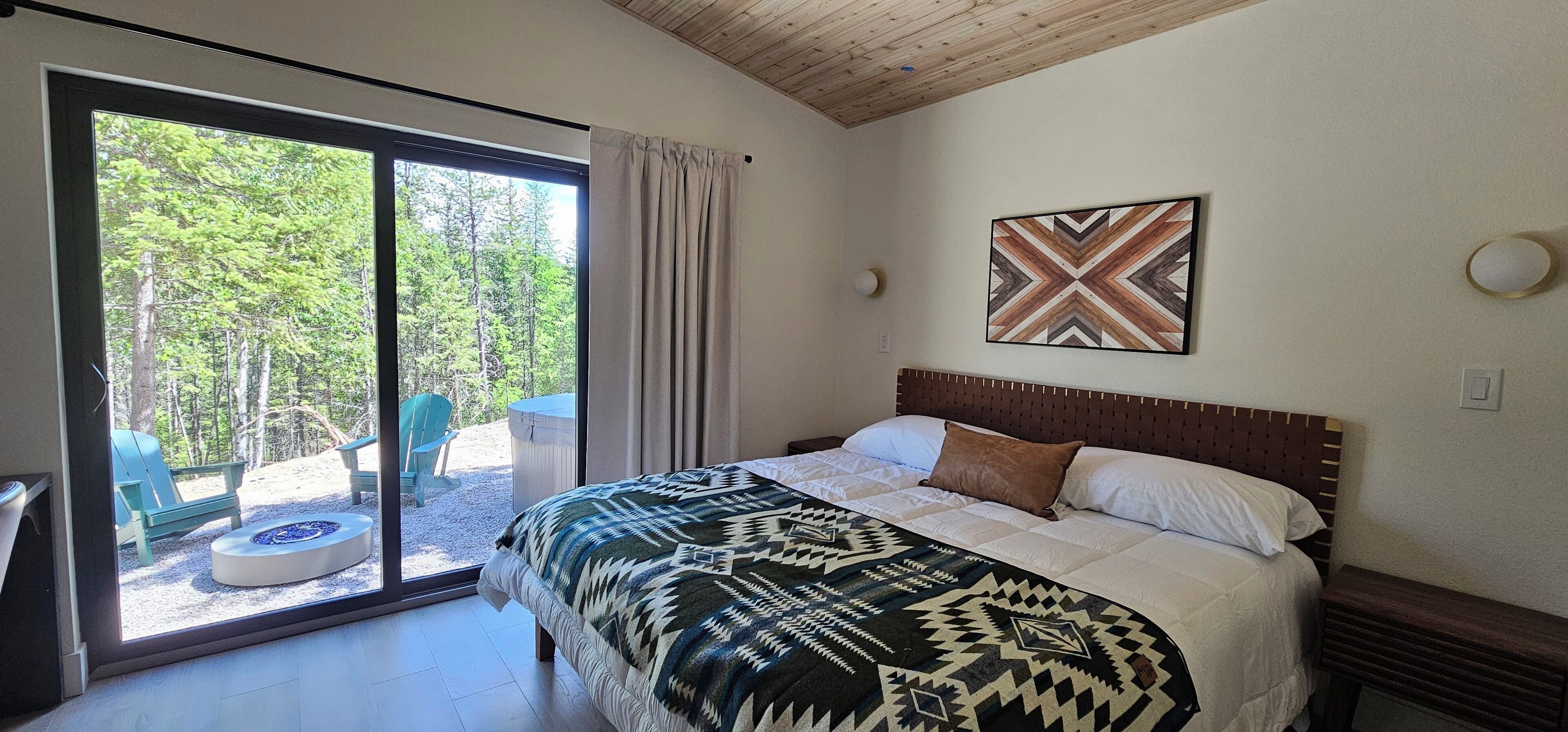 A bedroom with a bed, a window, a chair, and a view of trees.