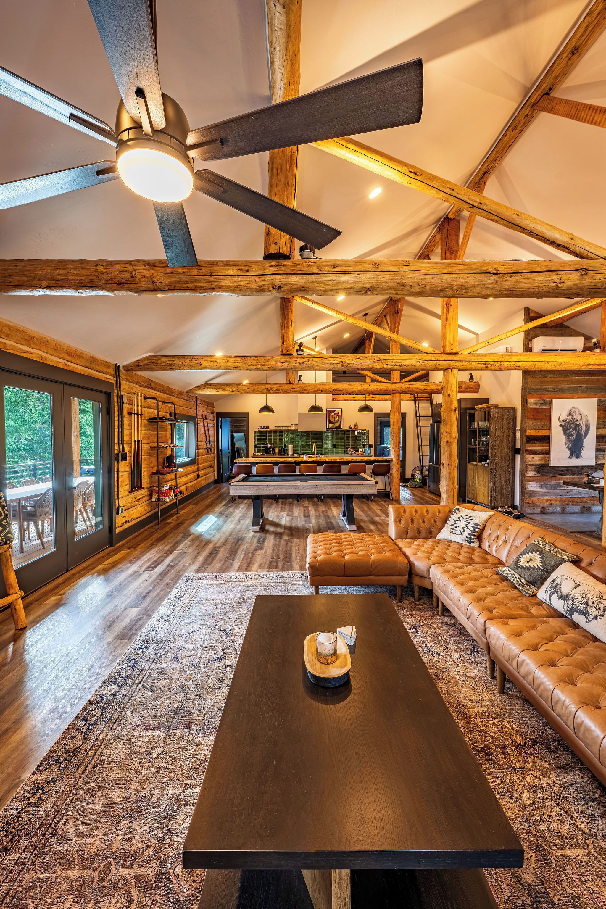 A spacious living area with a pool table, leather sofas, and a ceiling fan.