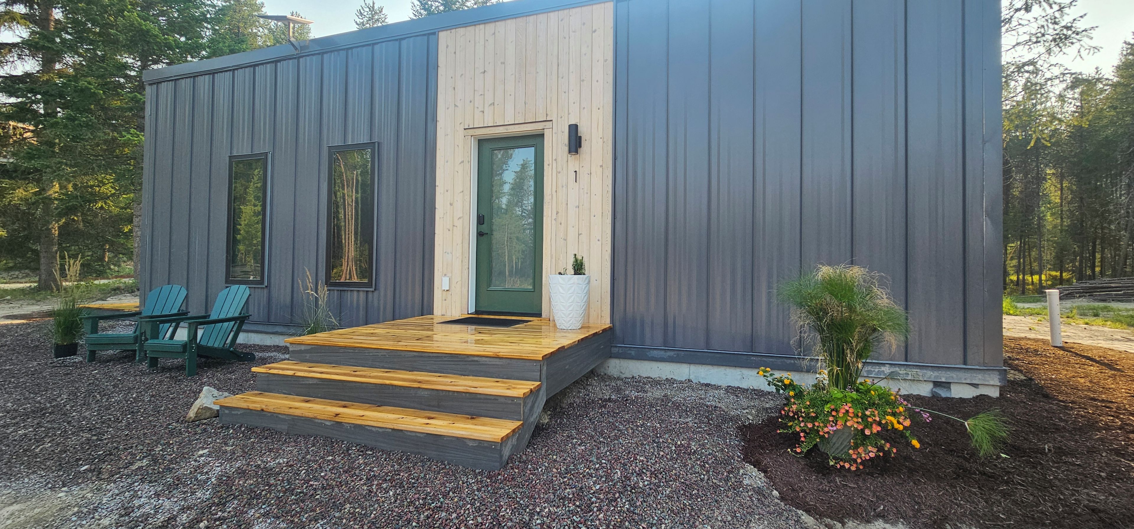 A modern cabin with a wooden deck, two windows, and a door.