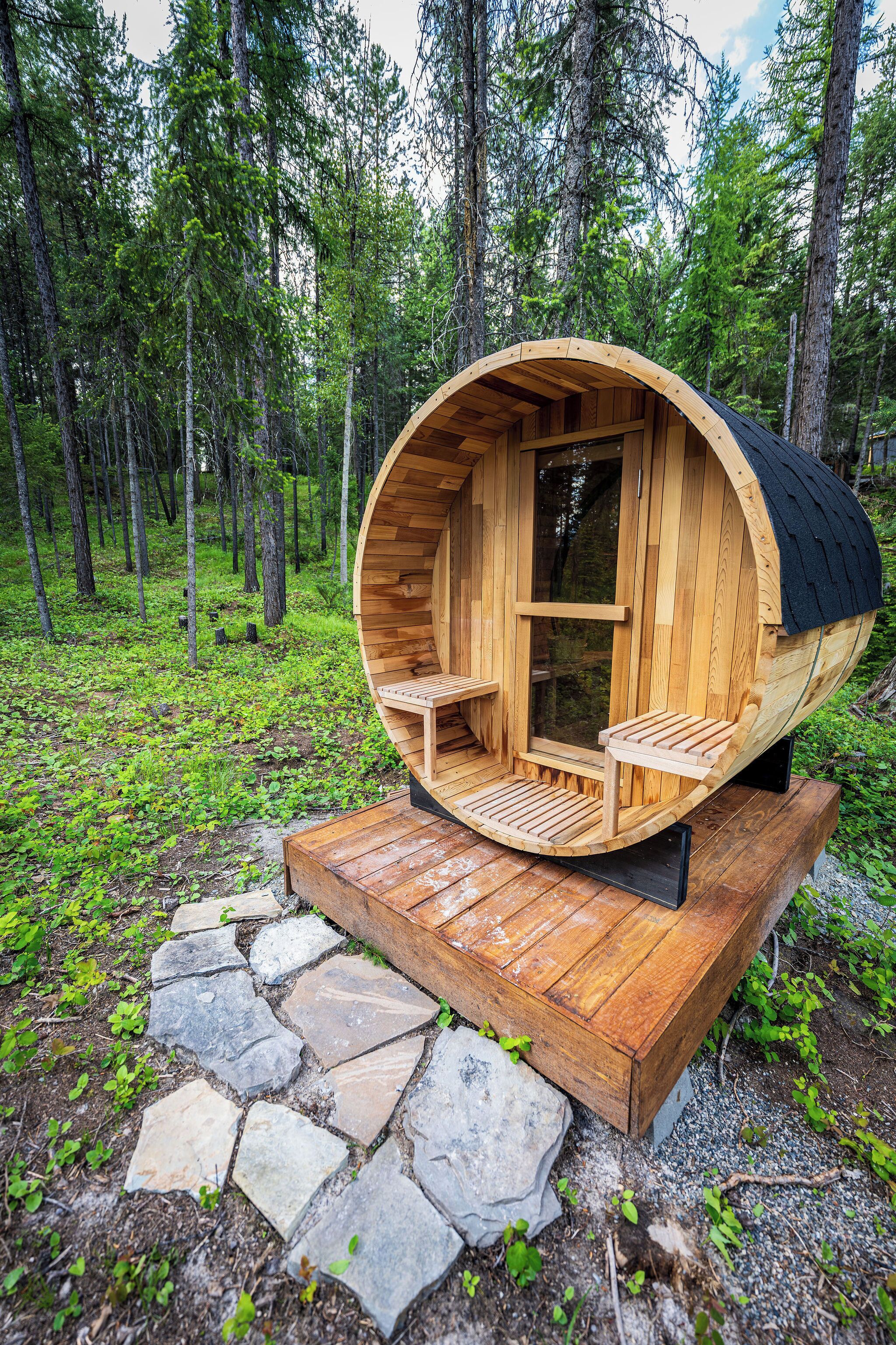 A wooden cylindrical structure with a bench and a table, surrounded by a forest.