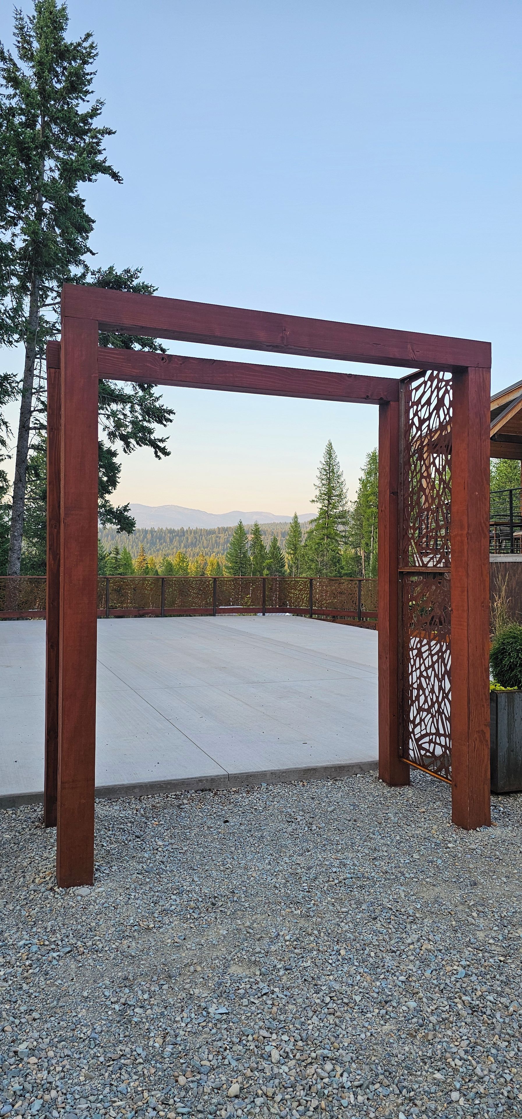 A wooden pergola structure with a view of a forest and mountains in the background.