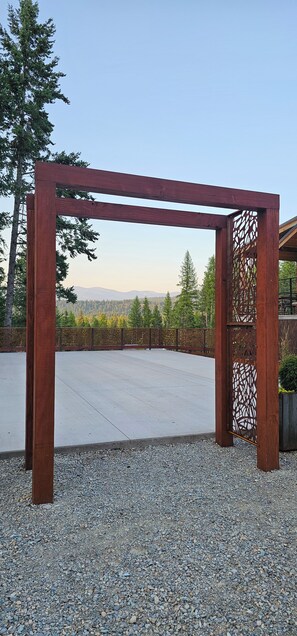 A wooden pergola structure with a view of a forest and mountains in the background. - NEW 9-cabin micro-resort, Full Buy Out-private, 2 hot tubs, 2 saunas,sleeps 24 (Whitefish)