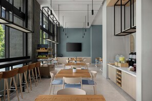 Un caffè moderno con tavoli e sedie in legno, un'area cucina e un'ampia finestra.