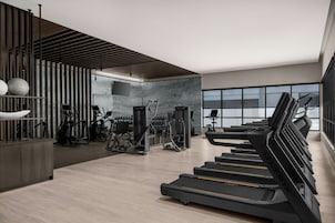 Un gimnasio moderno con cintas de correr, máquinas de pesas y un amplio ventanal que proporciona luz natural.