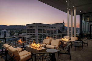 Terraço no telhado com área de estar ao ar livre, lareira e vista para a cidade.