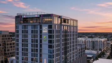 A modern hotel building with a prominent logo, multiple floors, and a rooftop terrace.