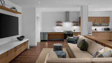 A modern living room with a flat-screen TV, a beige sofa with cushions, a coffee table, and wooden cabinets.