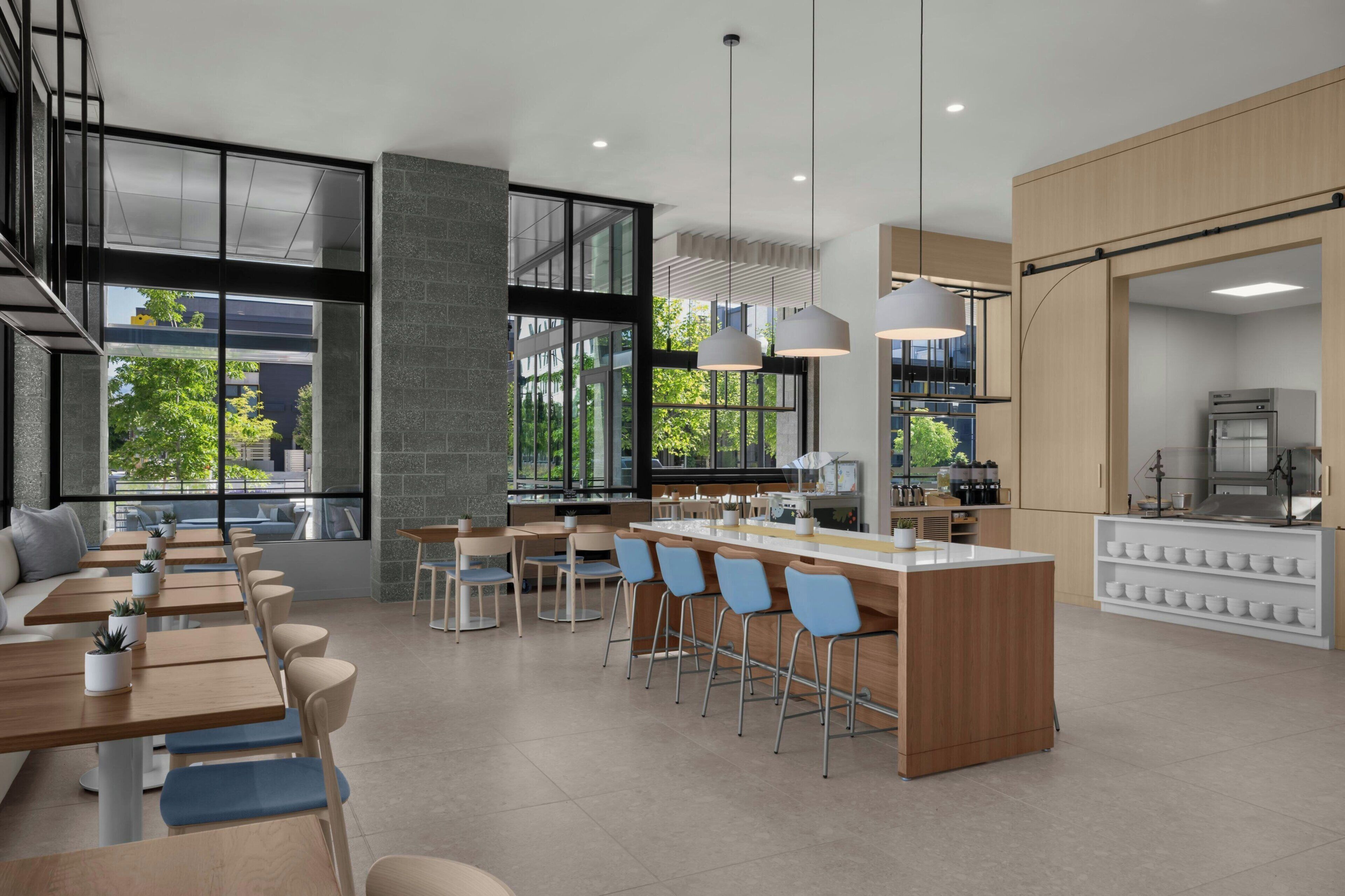 A modern kitchen with a central island, bar seating, and large windows.