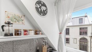 Une cuisine avec une carte du monde, une horloge et une fenêtre donnant sur des immeubles.