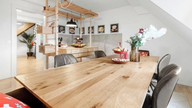 Un espace repas comprenant une table en bois, des chaises et un luminaire suspendu.